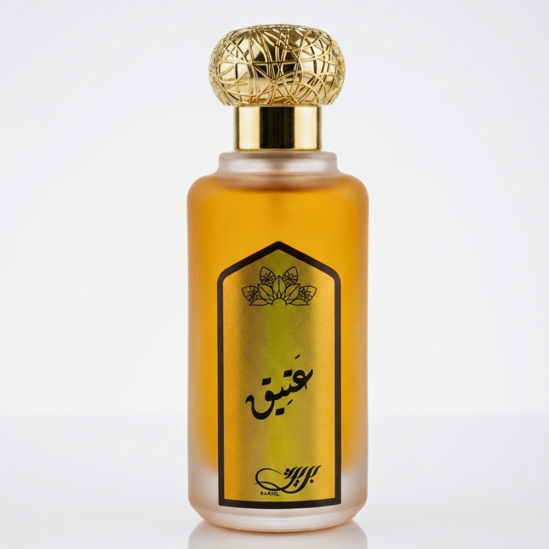 A bottle of Arabic perfume with a frosted glass body showing golden amber liquid inside, a gold label with black Arabic calligraphy, and a textured spherical gold cap, set against a clean white background.